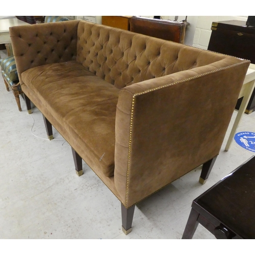 23 - A modern brown fabric button upholstered, box design three person settee, raised on mahogany block l... 