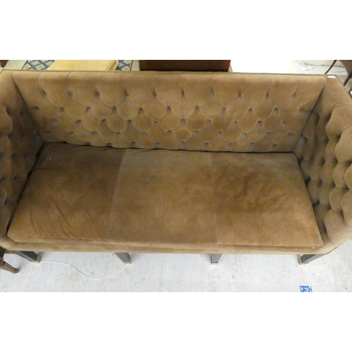 23 - A modern brown fabric button upholstered, box design three person settee, raised on mahogany block l... 