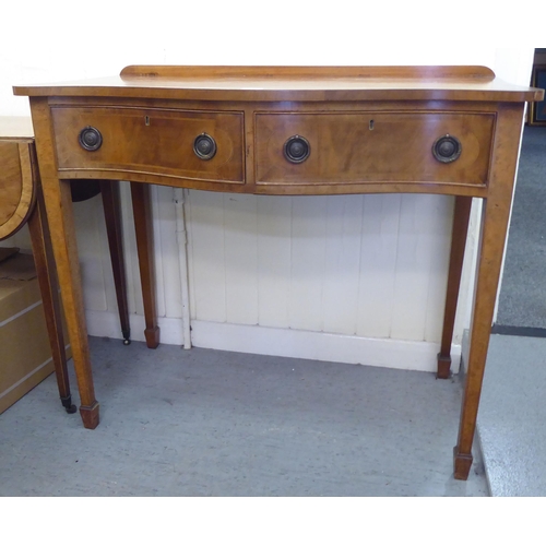 304 - A mid 20thC mahogany serpentine front cutlery table with two drawers, raised on square, tapered legs... 