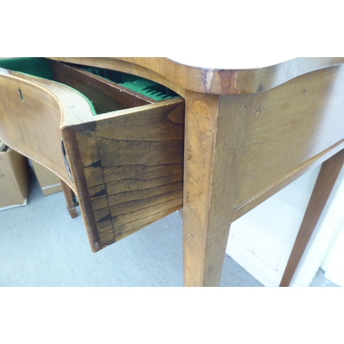 304 - A mid 20thC mahogany serpentine front cutlery table with two drawers, raised on square, tapered legs... 