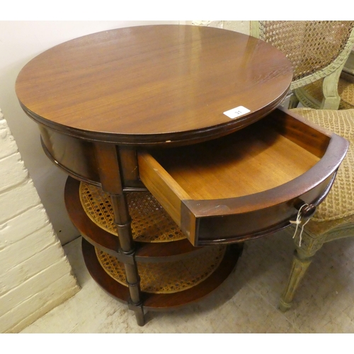 31 - A modern mahogany finished occasional table with a frieze drawer, over two caned platforms, raised o... 