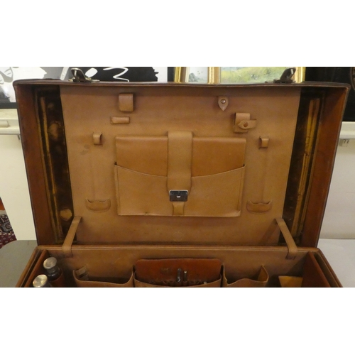 56 - A gentleman's stitched brown hide vanity case, the hinged lid enclosing a fitted interior with silve... 