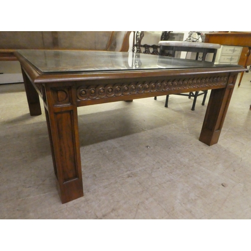 93 - A modern oak coffee/centre table with a carved frieze, raised on block legs  20