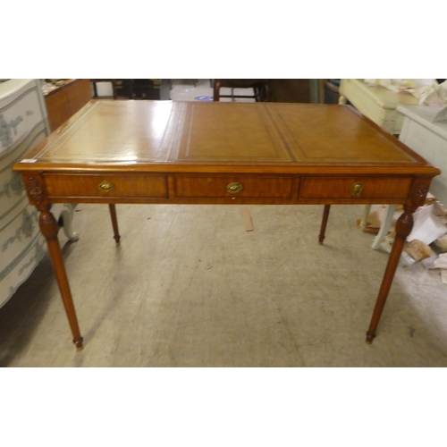 94 - A modern mahogany desk, the top set with a tooled brown hide scriber, over three drawers, raised on ... 