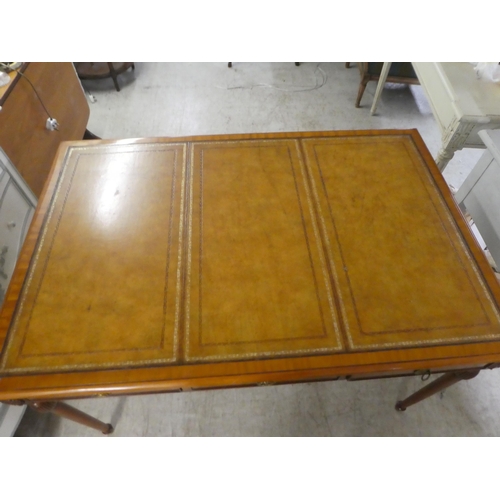 94 - A modern mahogany desk, the top set with a tooled brown hide scriber, over three drawers, raised on ... 