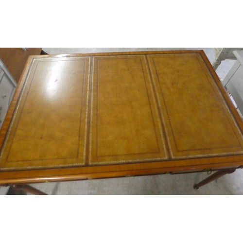 94 - A modern mahogany desk, the top set with a tooled brown hide scriber, over three drawers, raised on ... 