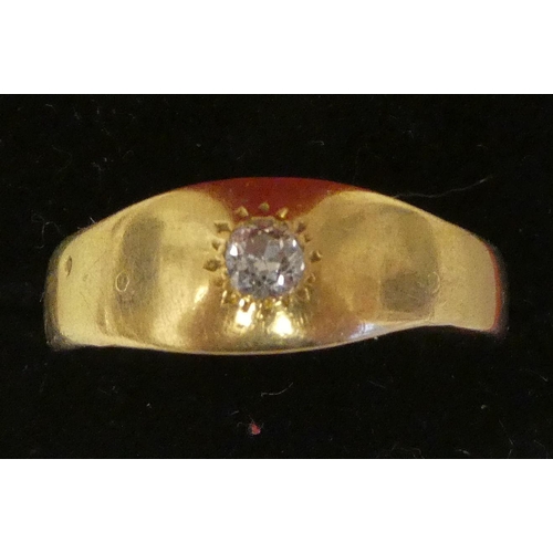 129 - A gold coloured metal ring, rubover set with a single diamond