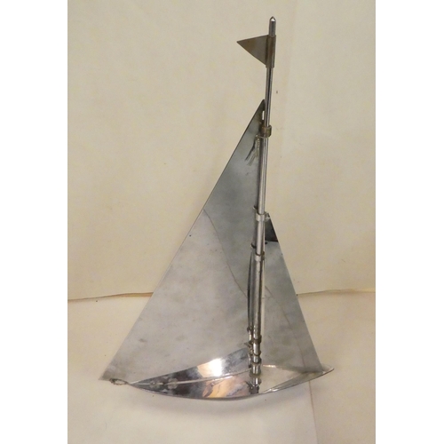 140 - A mid 20thC painted and polished stainless steel novelty table lighter, fashioned as a yacht under s... 