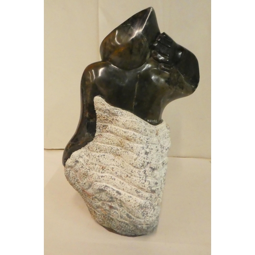 20 - M Fombe - a carved hardstone figure  bears a signature  13
