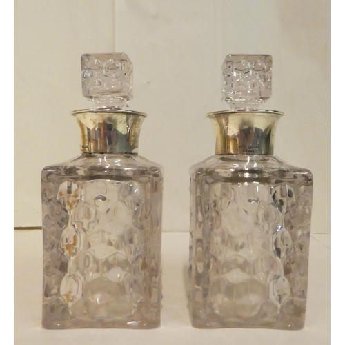 215 - Two moulded, shouldered, square glass decanters with silver collars  modern Birmingham marks