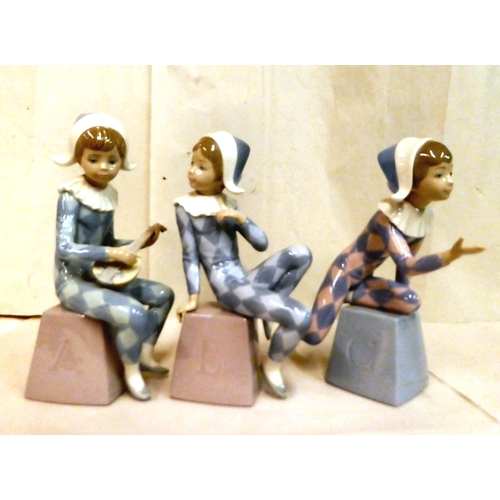 224 - A set of three Lladro porcelain figures, children in harlequin costumes, seated on A, B, C bricks&nb... 