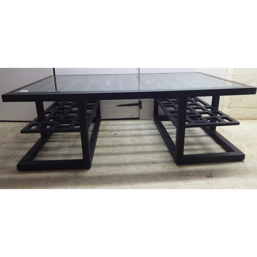 322 - A modern Chinese inspired, black painted coffee table with a glass inset top, on a plinth  18