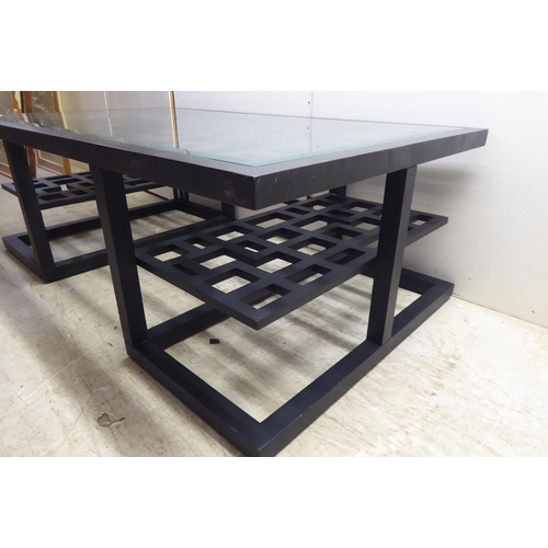 322 - A modern Chinese inspired, black painted coffee table with a glass inset top, on a plinth  18