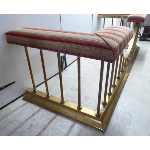 323 - A 20thC reproduction of a lacquered brass club fender with stud upholstered, cushioned fabric corner... 