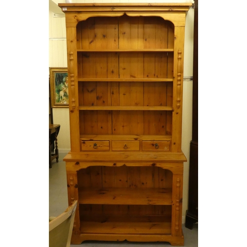 74 - A 20thC two-part pine dresser with an arrangement of open shelves and in-line drawers, raised on bra... 