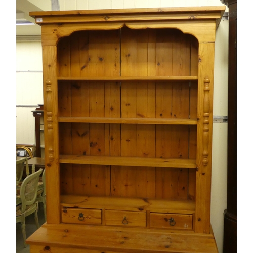 74 - A 20thC two-part pine dresser with an arrangement of open shelves and in-line drawers, raised on bra... 