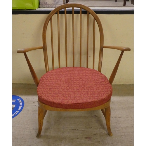 79 - An Ercol stained beech and elm framed, hoop and spindled back, low open arm chair, raised on turned ... 