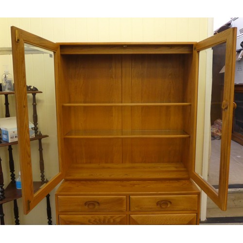 43 - An Ercol blond elm two-part cabinet, the upper section with two glazed doors, enclosing two height a... 