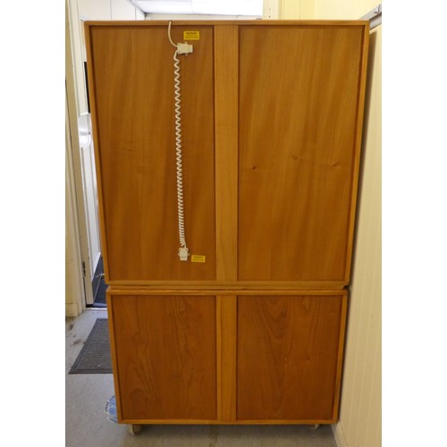 43 - An Ercol blond elm two-part cabinet, the upper section with two glazed doors, enclosing two height a... 