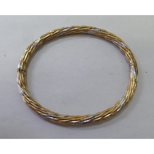 86 - A bi-coloured metal twist bangle  stamped 9k