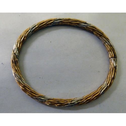 86 - A bi-coloured metal twist bangle  stamped 9k