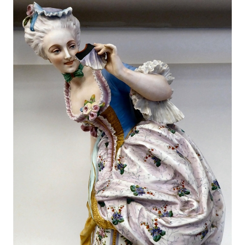 323 - A late 19thC French ceramic figure, a fashionable young lady wearing a floral skirt with a powder bl... 