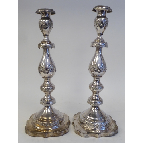 1 - A pair of silver candlesticks, each with a detachable downturned sconce, over a multiple vase design... 