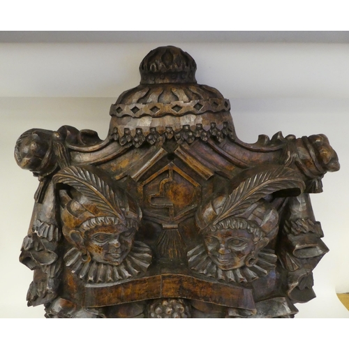 23 - An ornately carved and stained wooden wall plaque, featuring a pair of native busts, wearing identic... 