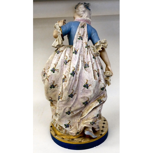 323 - A late 19thC French ceramic figure, a fashionable young lady wearing a floral skirt with a powder bl... 