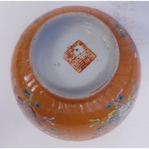 343 - A Chinese porcelain, ribbed, footed bowl, decorated in colours with stylised designs, on a pale ochr... 