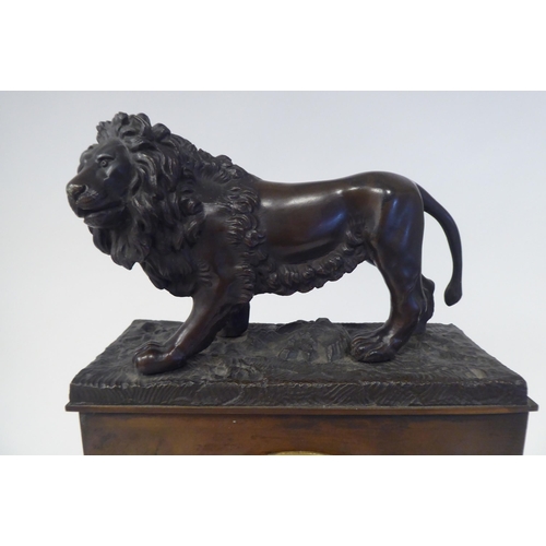 38 - A late 19th/early 20thC patinated and gilt bronze cased mantel clock, surmounted by a prowling lion,... 