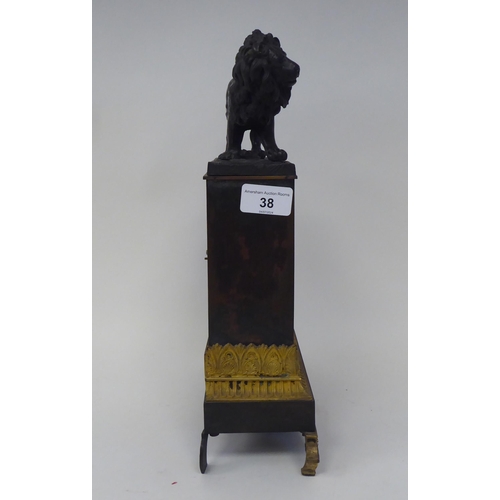 38 - A late 19th/early 20thC patinated and gilt bronze cased mantel clock, surmounted by a prowling lion,... 