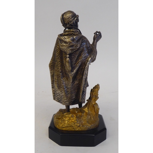 60 - A late 19thC Continental cast and bicoloured metal figure, a young itinerant salesman, on a black sl... 