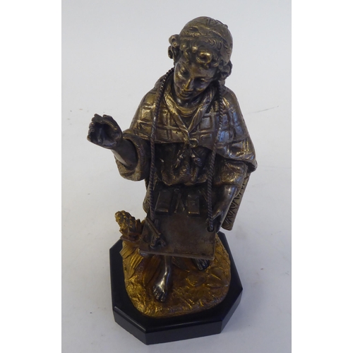 60 - A late 19thC Continental cast and bicoloured metal figure, a young itinerant salesman, on a black sl... 