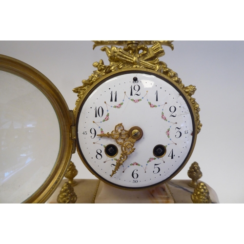 81 - A late 19th/early 20thC French mottled pink marble and gilt metal mounted, three piece clock garnitu... 