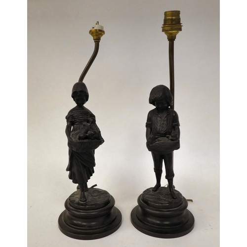 84 - A pair of cast and patinated bronze table lamps, depicting figures, a boy and a girl, carrying baske... 