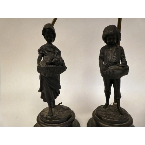 84 - A pair of cast and patinated bronze table lamps, depicting figures, a boy and a girl, carrying baske... 