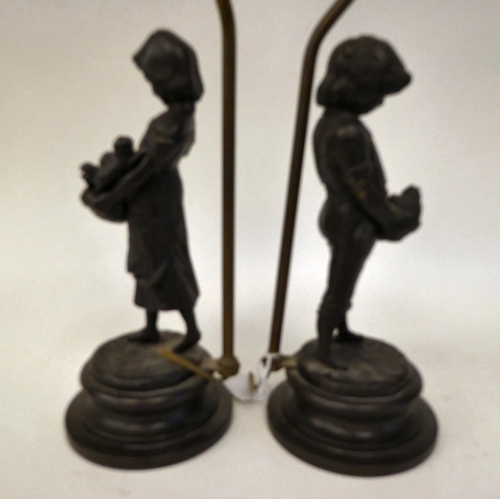 84 - A pair of cast and patinated bronze table lamps, depicting figures, a boy and a girl, carrying baske... 