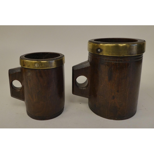 88 - Two, almost identical, Victorian one-piece cylindrical oak mugs with integral handles, applied brass... 