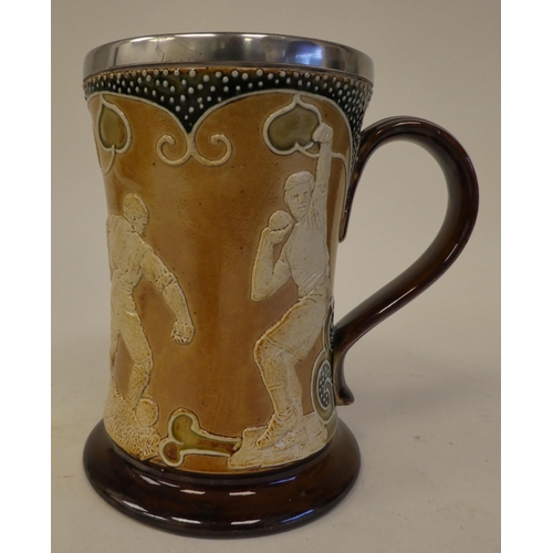 98 - An Art Nouveau Royal Doulton stoneware mug of waisted form, decorated in slip with field event athle... 