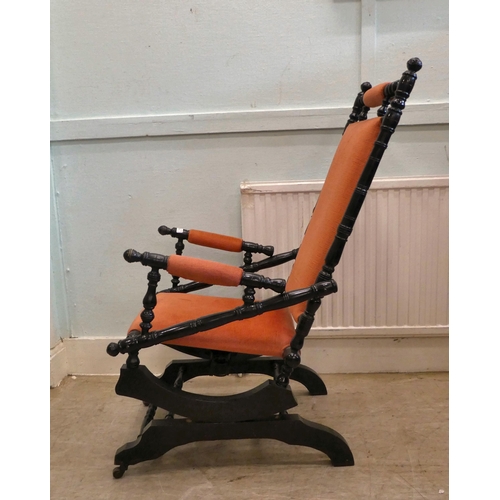 13 - A 20thC American design, black painted rocking chair with fabric upholstered back, arms and seat, on... 