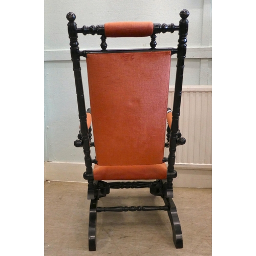 13 - A 20thC American design, black painted rocking chair with fabric upholstered back, arms and seat, on... 