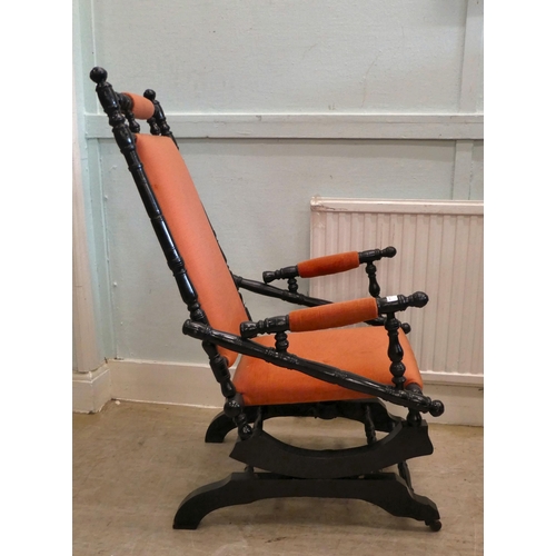 13 - A 20thC American design, black painted rocking chair with fabric upholstered back, arms and seat, on... 