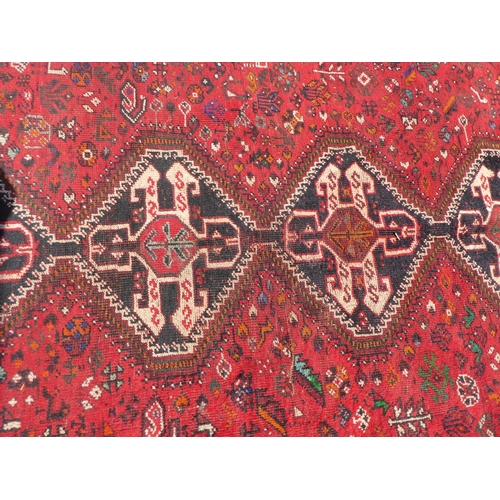 163 - A Persian rug, decorated with five central, diamond shaped medallions, bordered by repeating designs... 