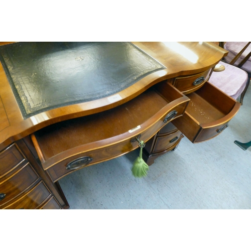 368 - A modern mahogany desk, the top set with a tooled green hide scriber, over two banks of four graduat... 