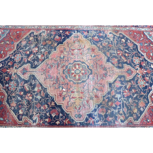 81 - A Persian rug, decorated with a central diamond shaped motif, bordered by stylised designs, on a mai... 