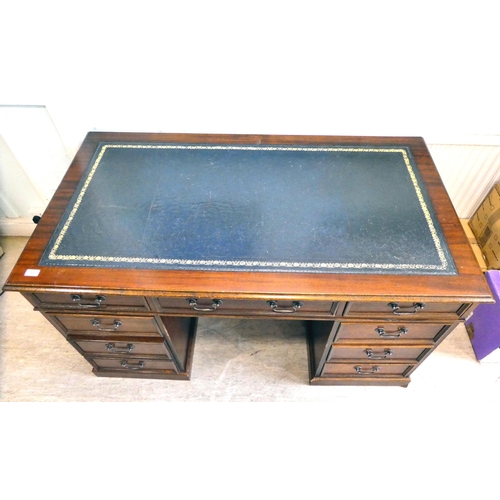 85 - A late 20thC Victorian style mahogany finished, nine drawer, twin pedestal desk with a tooled, blue ... 