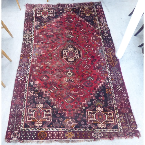 86 - A Persian Shiraz rug, decorated with repeating stylised designs, on a red ground  61