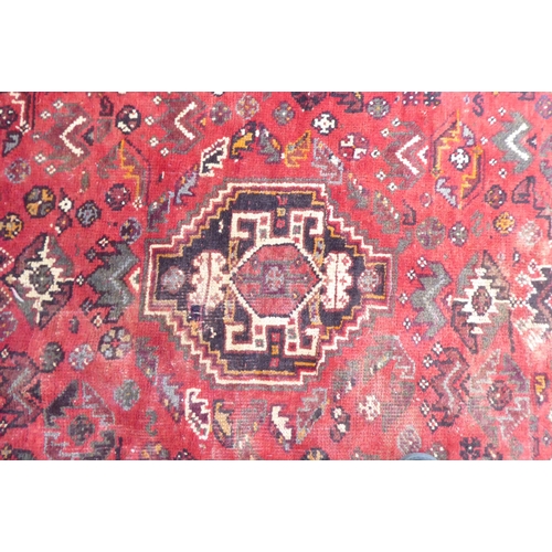 86 - A Persian Shiraz rug, decorated with repeating stylised designs, on a red ground  61