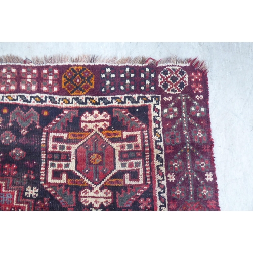 86 - A Persian Shiraz rug, decorated with repeating stylised designs, on a red ground  61